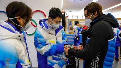 Volunteers trade pins inside the dining hall at the Yanqing Olympic Village in Beijing, China, February 11, 2022 