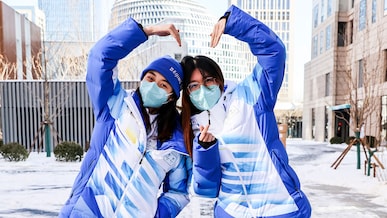 Volunteers strike a pose at the Beijing Olympic Village in Beijing, China, February 14, 2022. 