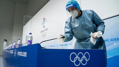 Le personnel du protocole Covid nettoie la salle de conférence de presse de l'IBC pendant les Jeux Olympiques d'hiver de Beijing 2022